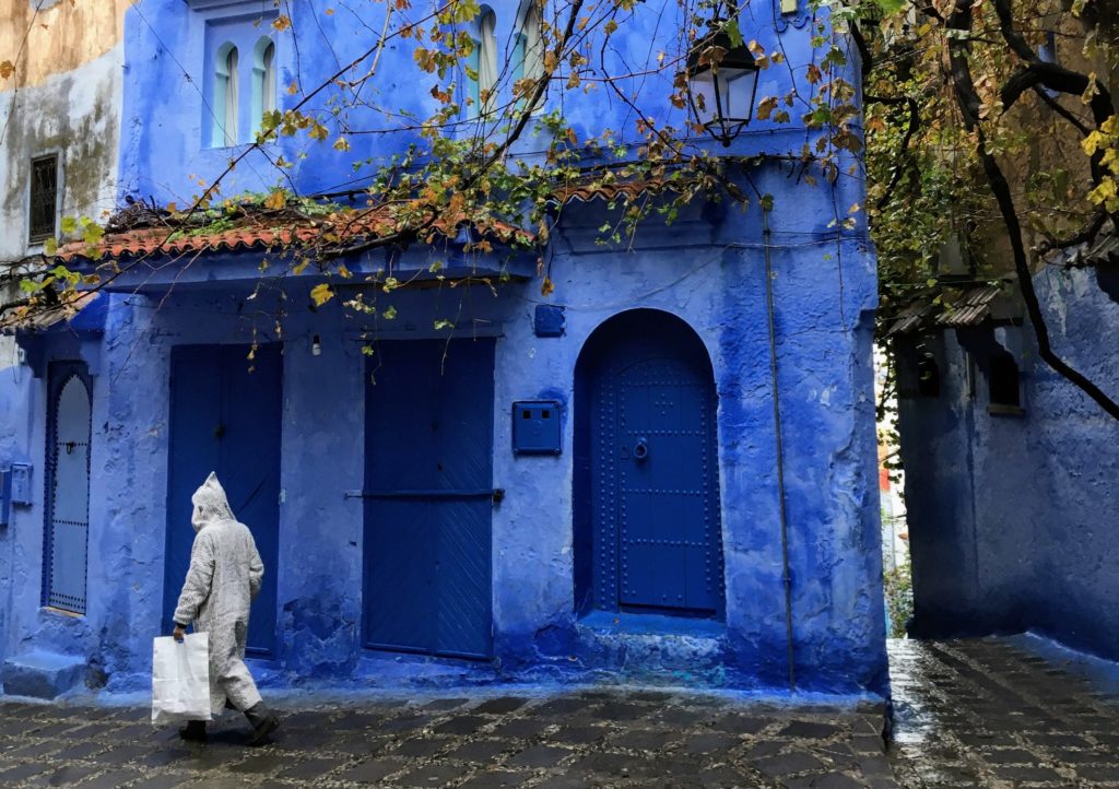 Blue doorways and blue buildings in Chefchaouen, Morocco with a local Moroccan walking by