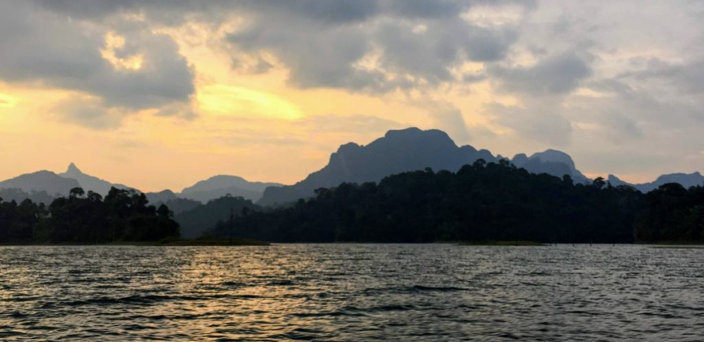 Sunset through the clouds at Khao Sok National Park lake